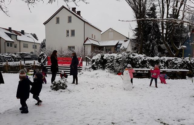 Kinder bauen im Schnee einen Schneemann