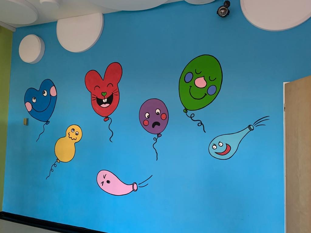 Bunt gemalte Luftballons an einer Wand im Inneren der Kita
