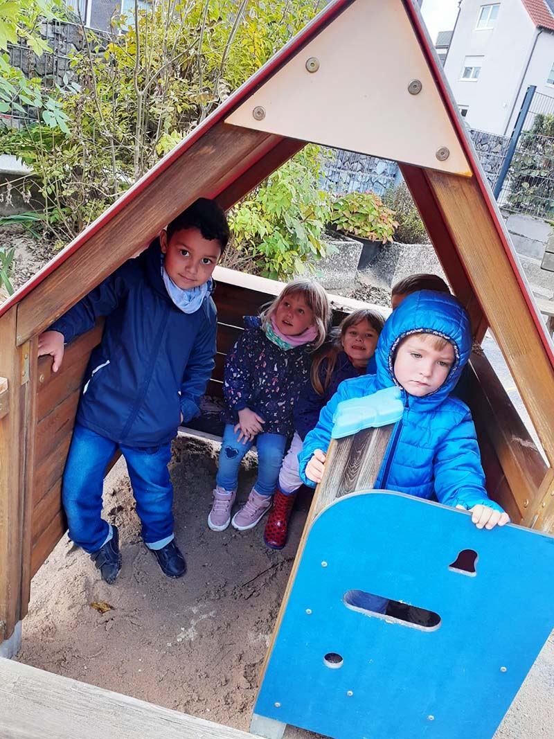 Kleines Spielhäuschen aus Holz auf dem Außengelände