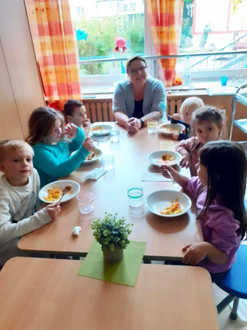 Kinder sitzen beim gemeinsamen Essen am gedeckten Tisch
