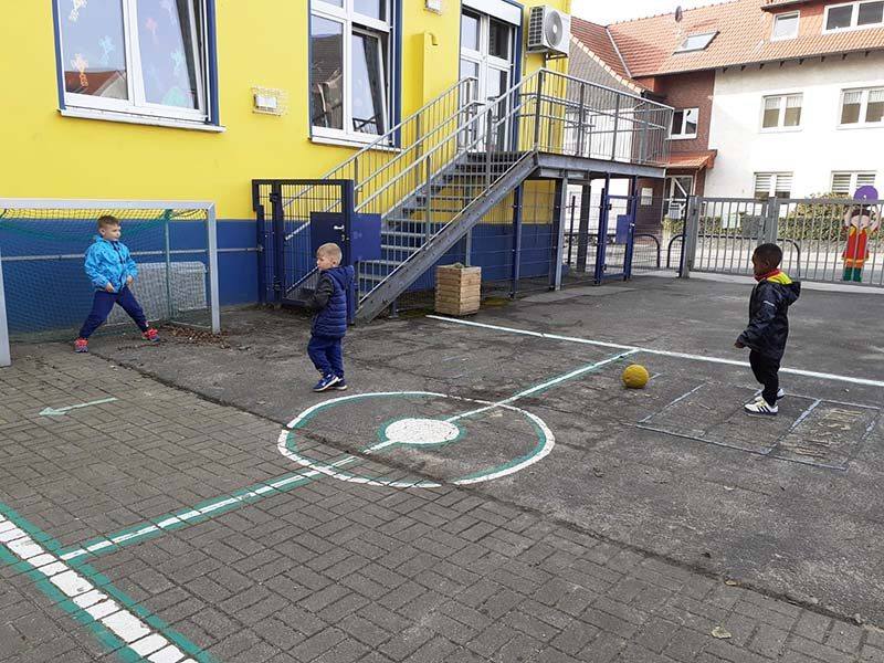 Kinder spielen zusammen auf dem Hof vor dem Haus